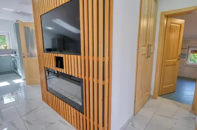 a living room with a fireplace with a tv on a wall at Hisa idej in Sežana