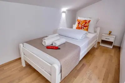 a white bed with two towels on top of it at Hisa idej in Sežana