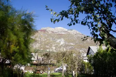 a mountain in the background of a town with trees at Apartment House Anton with free parking in Bovec