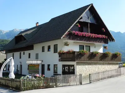 a white house with flowers on the balcony at Apartments Štros in Bohinj