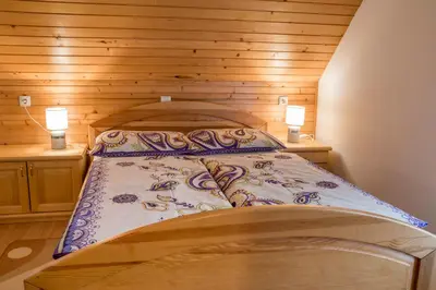 a bedroom with a bed with wooden walls and two lamps at Apartments Štros in Bohinj