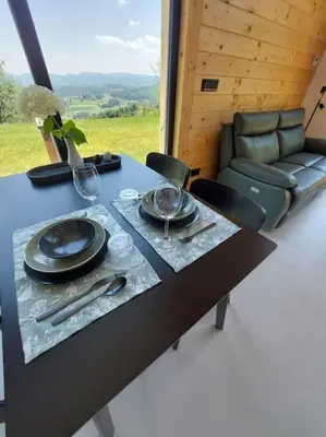 a table with plates and wine glasses and a couch at HERBALIJA Apartment Amalija - in the embrace of wellbeing in Podčetrtek