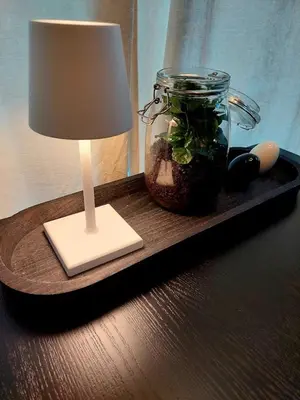 a table with a lamp and a jar with a plant in it at HERBALIJA Apartment Amalija - in the embrace of wellbeing in Podčetrtek