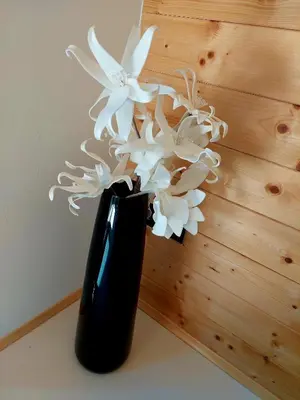 a black vase filled with white flowers on a table at HERBALIJA Apartment Amalija - in the embrace of wellbeing in Podčetrtek