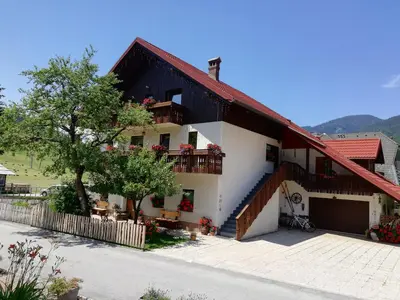 a white house with a red roof at Apartments & Rooms Smučka in Kranjska Gora