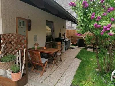 a patio with a wooden table and chairs in a yard at Apartments & Rooms Smučka in Kranjska Gora
