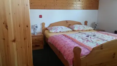 a bedroom with a wooden bed with a wooden headboard at Apartments & Rooms Smučka in Kranjska Gora