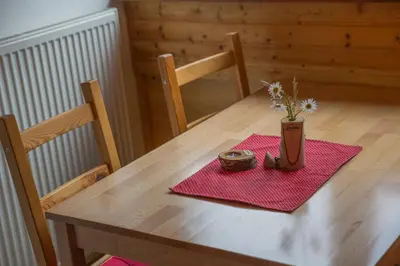 a wooden table with a vase of flowers on a table at Apartments & Rooms Smučka in Kranjska Gora