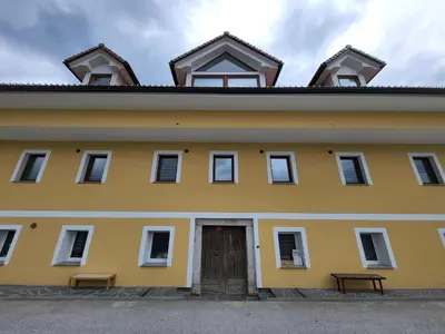 a yellow building with a door and two benches at Stara Pošta Apartment 1 in Grosuplje