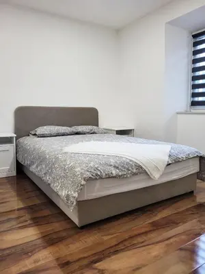 a bed in a white bedroom with a wooden floor at Stara Pošta Apartment 5 in Grosuplje