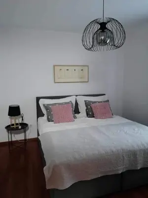 a bedroom with a bed with pink pillows and a chandelier at Apartma Bistrica in Slovenska Bistrica