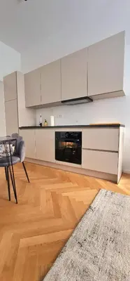 a kitchen with white cabinets and a table and a couch at Apartment Tivoli in Ljubljana