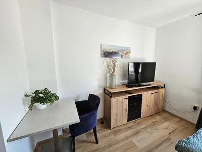 a living room with a table and a tv on a wooden cabinet at soba v Pekrski vili in Limbuš