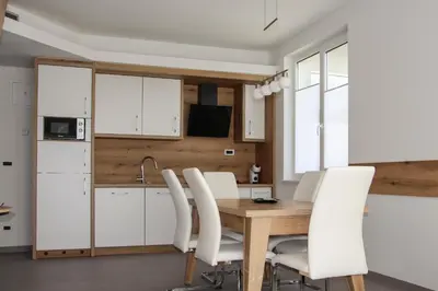 a kitchen with white cabinets and a wooden table and white chairs at Apartment Simona in Kranjska Gora