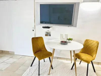 a white table with two chairs and a tv on a wall at Ground Floor Apt with a Pool and Terrace in Pesnica pri Mariboru