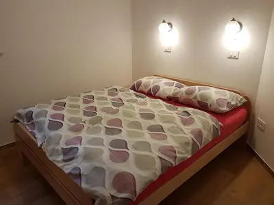 a bed in a bedroom with two lights on the wall at Garden Apartments Maria in Bled