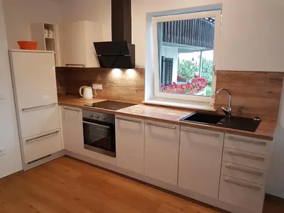 a kitchen with white cabinets and a sink and a window at Garden Apartments Maria in Bled