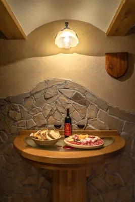 a table with a plate of food and a bottle of wine at Vineyard Cottage Krivic in Trebelno