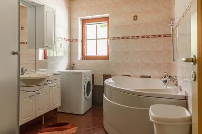 a bathroom with a tub and a sink and a washing machine at Apartments Petek in Gornji Grad