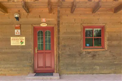 a red door and two windows on a wooden building at Apartments Petek in Gornji Grad