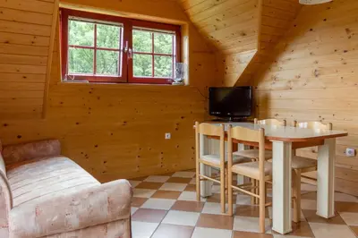 a living room with a table and a tv in a cabin at Apartments Petek in Gornji Grad