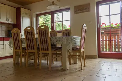 a kitchen with a table and chairs and windows at Apartments Petek in Gornji Grad