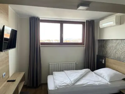 a small bedroom with a bed and a window at Hotel Roškar in Ptuj