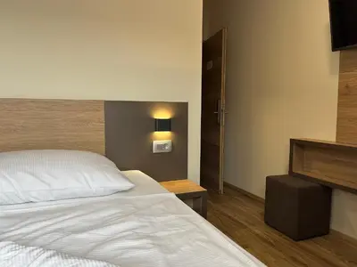 a bedroom with a white bed and a night stand at Hotel Roškar in Ptuj