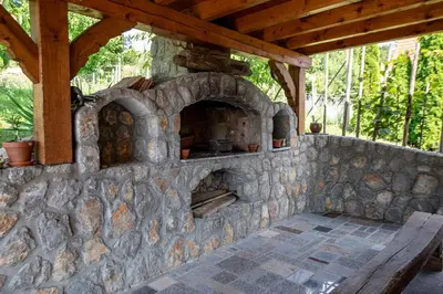 an outdoor oven with a stone wall and a bench at Vineyard Cottage Pod Piramido in Dobrnič