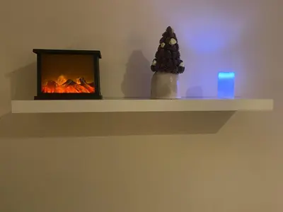 a shelf with a fireplace with a christmas tree on it at Apartment La Vie in Maribor