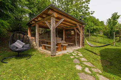 a wooden gazebo with a bench in the grass at Vineyard Cottage Rataj 1 in Novo Mesto