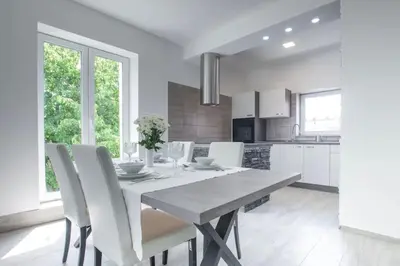 a white kitchen with a table and white chairs at 2022 Central Apartment Maribor (Garden + Parking) in Maribor
