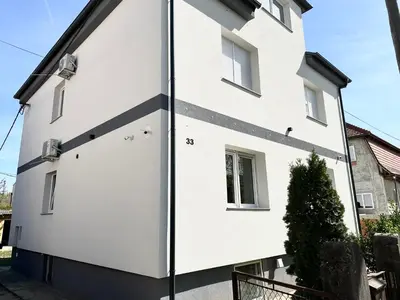 a white house with a black stripe on the side at 2022 Central Apartment Maribor (Garden + Parking) in Maribor