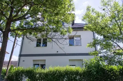 a white building with trees in front of it at 2022 Central Apartment Maribor (Garden + Parking) in Maribor
