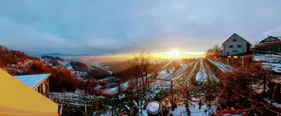 a house on a snowy hill with the sunset in the background at Vineyard Cottage Vercek in Novo Mesto