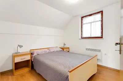 a white bedroom with a bed and a window at Vineyard Cottage Tramte in Škocjan