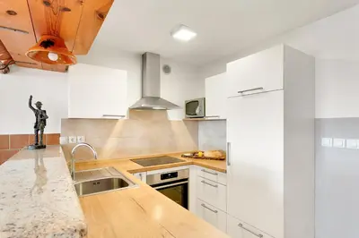 a kitchen with white cabinets and a wooden counter top at Vineyard Cottage Tramte in Škocjan