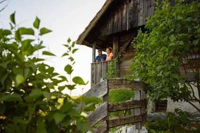 two people standing on the balcony of a building at Vineyard Cottage Skatlar in Otočec