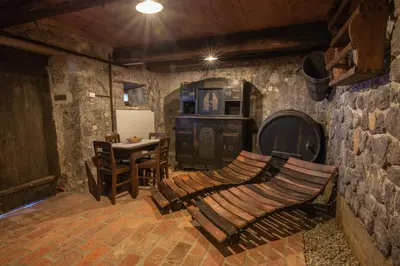 a room with a stone wall with a wooden bench at Vineyard Cottage Skatlar in Otočec