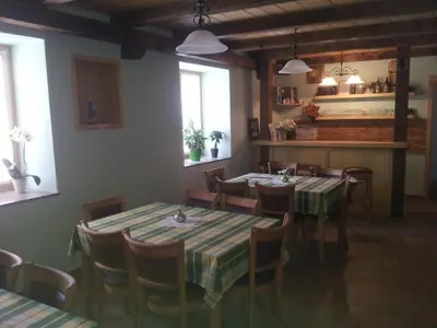 a dining room with tables and chairs and windows at Turistična kmetija Pri Požarju in Knežak