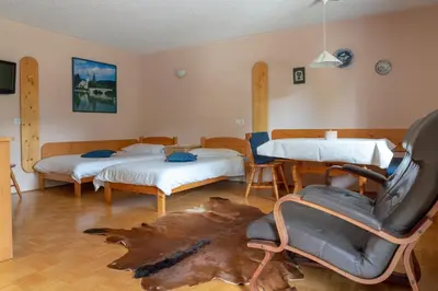 a room with two beds and a table and a chair at Apartments Maja by the river in Bohinj