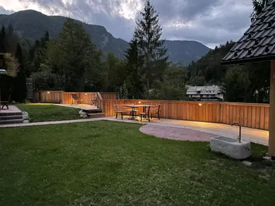 a backyard with a patio with a table and a fence at Apartments Maja by the river in Bohinj