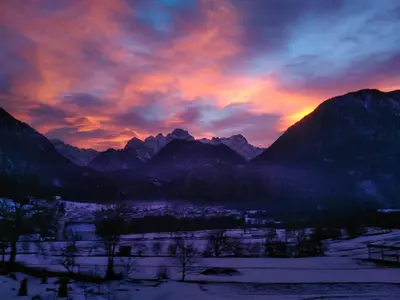 a sunset over a snow covered mountain range at Apartments Mas in Dovje