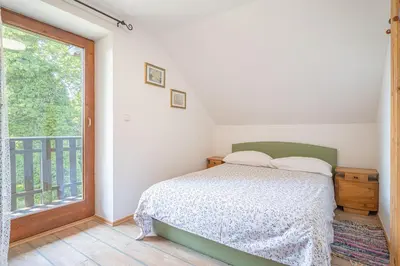 a bedroom with a bed and a large window at Vineyard Cottage Vrbek in Roginska Gorca