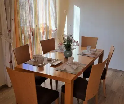 a wooden dining room table with chairs and a vase on it at Apartments AD Radenci in Radenci