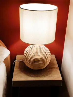 a lamp sitting on a wooden table next to a bed at POČITNIŠKA HIŠA SONČNI VRH in Spodnji Ivanjci