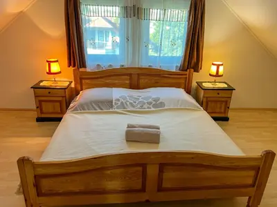 a bedroom with a large wooden bed with two lamps at POČITNIŠKA HIŠA SONČNI VRH in Spodnji Ivanjci
