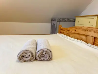 a bed with two rolled towels on it at POČITNIŠKA HIŠA SONČNI VRH in Spodnji Ivanjci