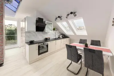 a kitchen with white cabinets and a table with chairs at Luiza's Apartment in Ljubljana