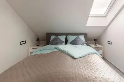 a bedroom with a bed with blue sheets and a window at Luiza's Apartment in Ljubljana